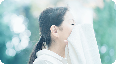 写真：タオルで顔を覆う女性